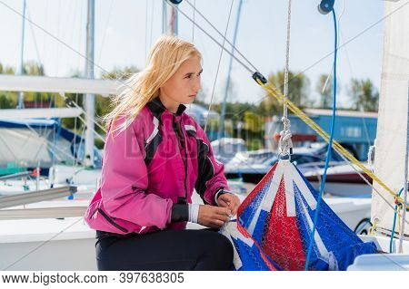 Womens River Regatta On A Sunny Day. A Young Blonde Sets Up The Rigging And Secures The Genaker Sail