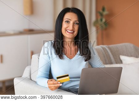 Easy Payment And Online Transaction. Smiling Mature Woman Ordering On Internet, Using Laptop, Showin