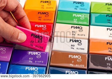 Tambov, Russian Federation - November 18, 2020 Woman Hand Taking Crimson Fimo Soft Modelling Clay Bl