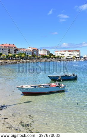 Portosin, Spain. June 30, 2020. Harbor And Coastal Village With Rowboats And Galician Fishing Vessel