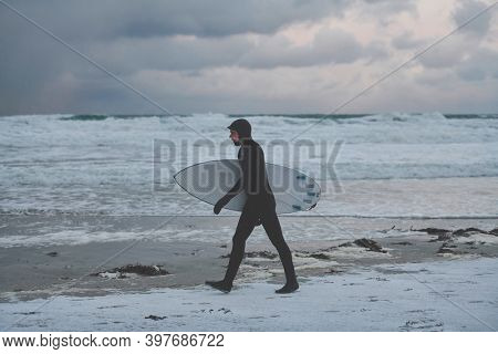 Arctic surfer going by beach after surfing