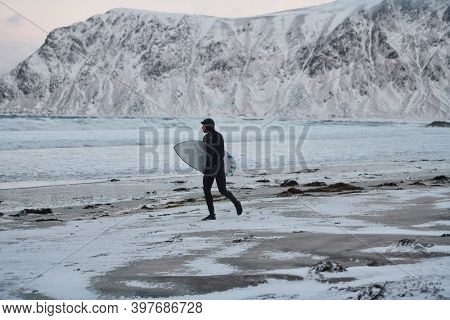 Arctic surfer going by beach after surfing