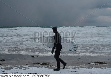 Arctic surfer going by beach after surfing