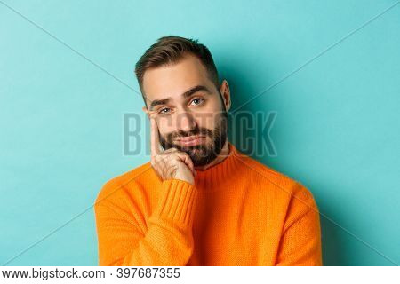 Close-up Of Unamused Sad Man Looking At Camera, Pouting And Leaning Face On Hand, Standing Over Ligh