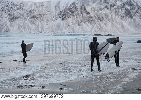 Arctic surfers going by beach after surfing