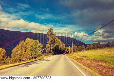 Mountain Road At Sunset With Cloudy Sky. Autumn Nature Norway After Rain. Rainbow Over Road