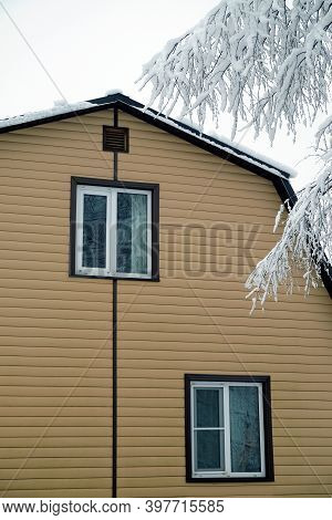 Upper Floor With Plastic Window  In Country House Wall Covered With Beige Siding And Brown Metal Roo