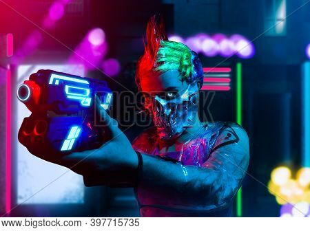 Crazy Killer Cyborg Woman With Mohawk Hairstyle In Spiked Skull Mask Aiming At Somebody With A Handg