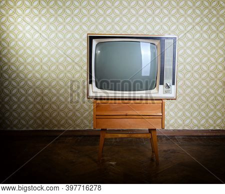 Retro tv on wooden case in room with vintage wallper and parquet