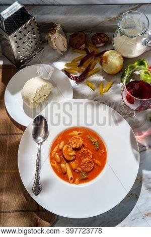 Creamy Italian Sausage Soup With Mozzarella Cheese Onions And Peppers Served With A Glass Of Red Win