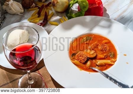 Creamy Italian Sausage Soup With Mozzarella Cheese Onions And Peppers Served With A Glass Of Red Win