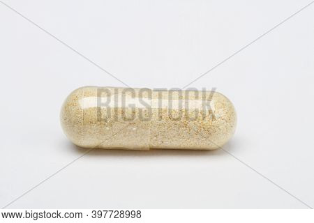 Single Transparent Capsule With Light Brown Ingredient Against A White Background