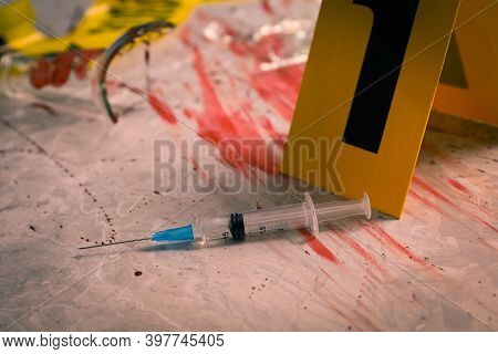 Syringe In Blood And Crime Scene Marker On Marble Table, Closeup