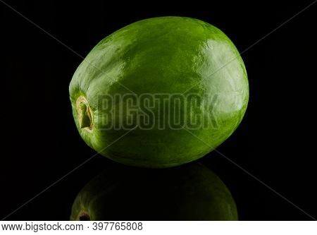 Green Round Papaya On A Black Background With Reflection.