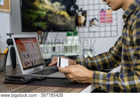 Asian Man Holding Credit Card And Typing Information On Internet With Laptop At Home, Online Shoppin