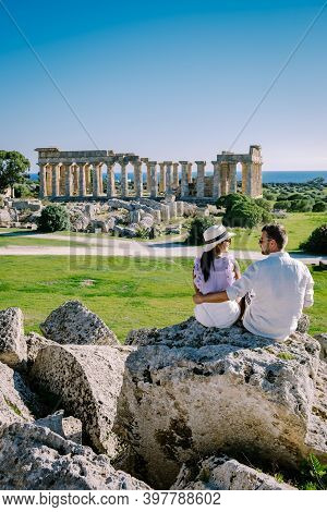 A Couple Visit Greek Temples At Selinunte During Vacation, View On Sea And Ruins Of Greek Columns In