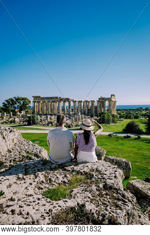 A Couple Visit Greek Temples At Selinunte During Vacation, View On Sea And Ruins Of Greek Columns In