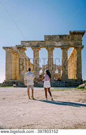 A Couple Visit Greek Temples At Selinunte During Vacation, View On Sea And Ruins Of Greek Columns In
