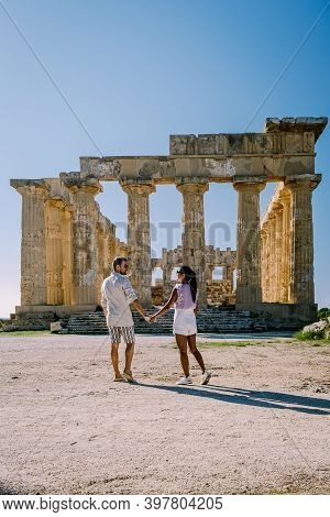 A Couple Visit Greek Temples At Selinunte During Vacation, View On Sea And Ruins Of Greek Columns In