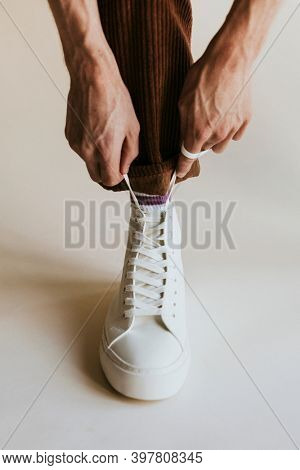 Man hands fixing shoelaces white high top shoes