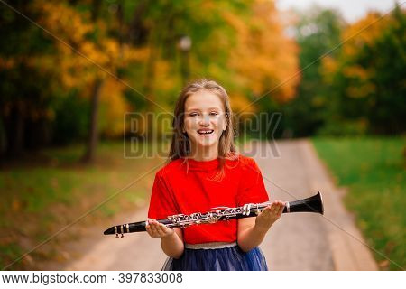 Young Attractive Girl Playing Clarinet, Ebony In Fall Park