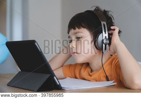 School Kid Wearing Headphone Listening The Teacher Teaching Online Class,child Boy Studying And Doin