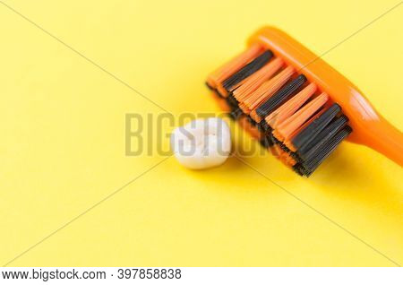 Tooth brush and deciduous milk child teeth on yellow background