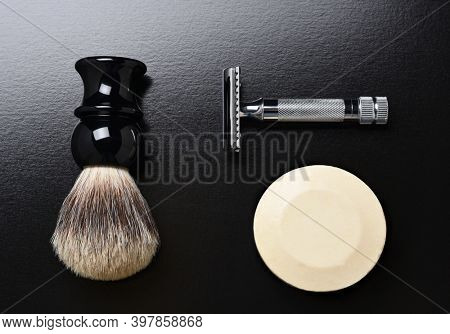 Flat Lay Shaving Still Life. A razor shaving brush and bar of soap on black.