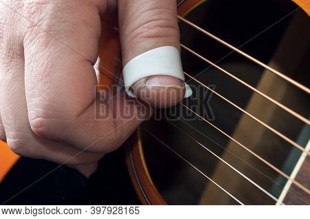 Detail Of A Guitar Player Hand Using A Thumbpick To Play Fingerstyle And Fingerpick Music