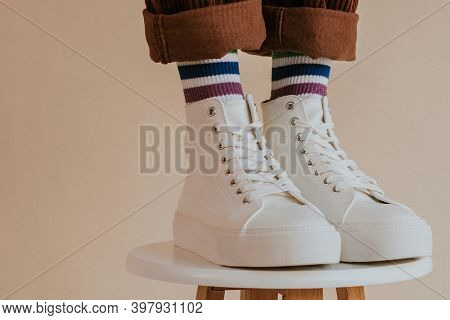 Man in white high top shoes standing on chair