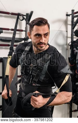 Young Smiling Athlete In Ems Suit Training With Suspension Rope