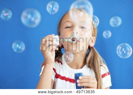 Muotokuva hauska kaunis pieni tyttö puhaltaa saippuakuplia