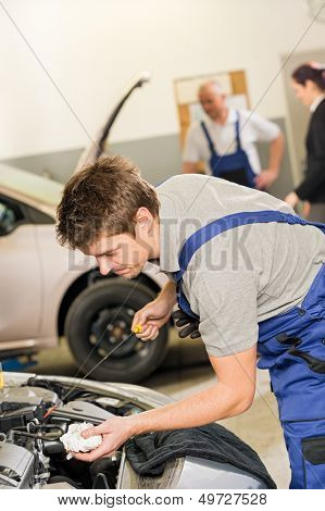 Portrait of repairman checking oil with dipstick