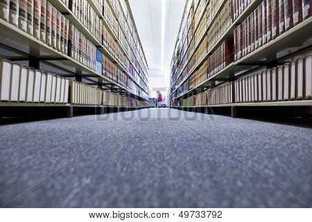 ระยะยิงของเพศหญิงในห้องสมุดมหาวิทยาลัย มีชั้นหนังสืออยู่เบื้องหน้า
