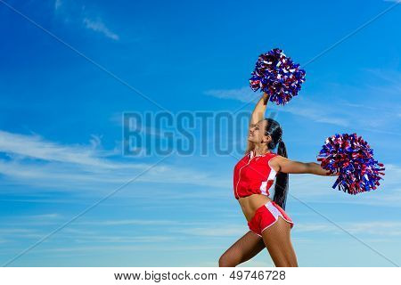 Young cheerleader in red costume with pampon