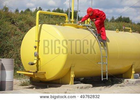 technician in red uniform working on large fuel tank 