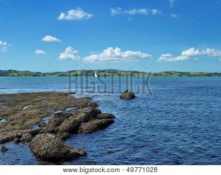 View From The Shore Onto The Sea With An Island In The Background