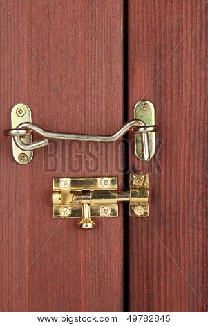 Metal hook and deadbolt in wooden door close-up