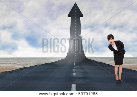 Surpised businesswoman bending against road turning into arrow