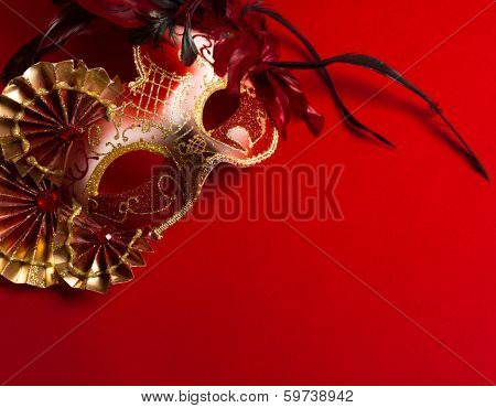 A red and gold venetian, mardi gras mask on a red bakground