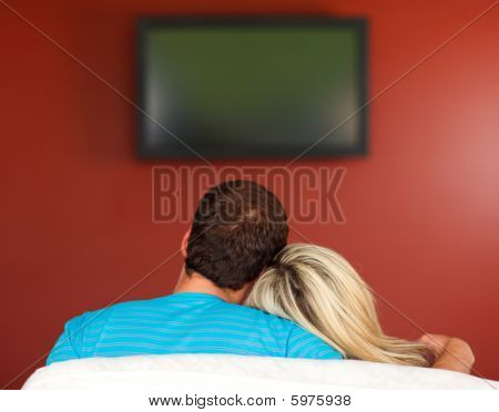 Couple Sitting On Couch Watching A Television At Home