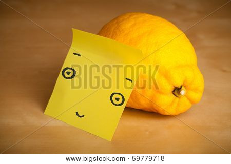 Drawn smiley face on a post-it note sticked on a lemon