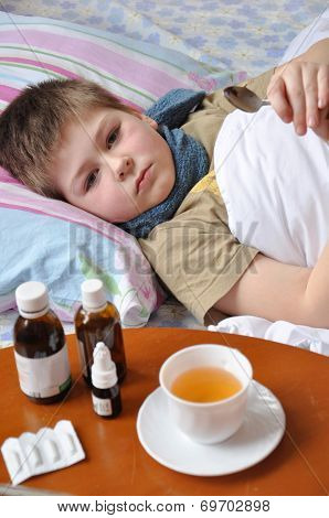 Sick Boy Lying In Bed. Drugs On The Table