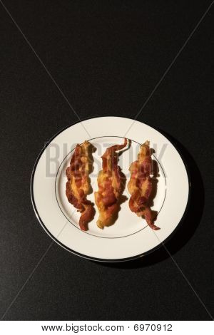 Tre strisce di Bacon cotto sulla piastra bianca