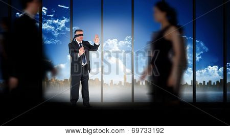 Mature businessman in a blindfold against room with large window looking on city skyline