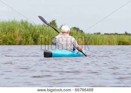 Man Paddling In A Blue Kayak