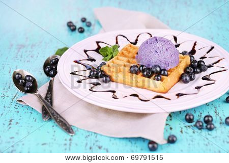 Tasty belgian waffles with ice cream on wooden table