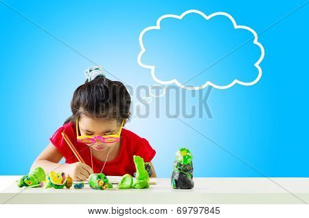 Little girl with a pencil thinking and writing something on table.