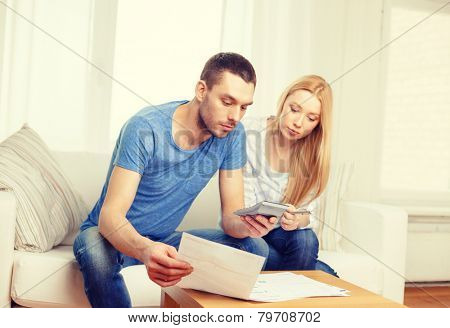 tax, finances, family, home and happiness concept - busy couple with papers and calculator at home