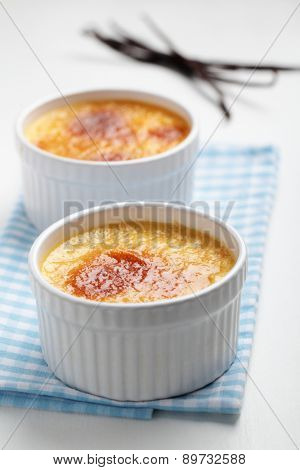 Two portions of vanilla creme brulee in ramekins
